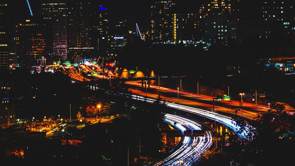 A bustling cityscape featuring vibrant light trails on a highway during the night, showcasing urban energy.